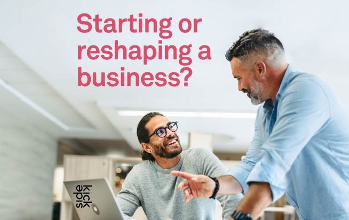 two men in an office discussion in front of laptop